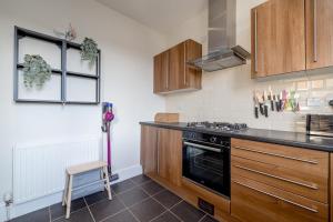 a kitchen with wooden cabinets and a stove top oven at Barnton Grove Getaway in Edinburgh +21 photos