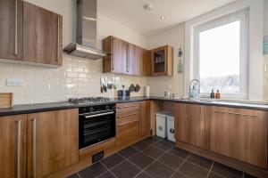 a large kitchen with wooden cabinets and a window at Barnton Grove Getaway in Edinburgh