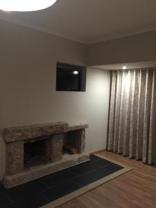 a living room with a stone fireplace and a flat screen tv at Casas do Terreiro in Seia