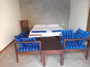 a room with a bed and two chairs and a table at Blu EDGE BEACH RESORT in Katuneriya
