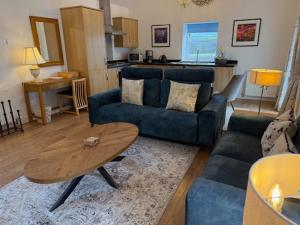 a living room with a blue couch and a table at Anniston Farm Cottages in Inverbervie