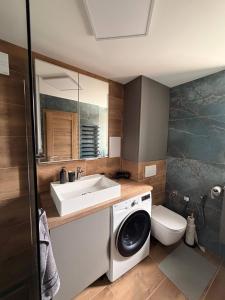 a bathroom with a sink and a washing machine at Lipa Apartmán in Tlmače