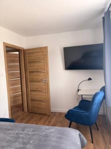 a bedroom with a blue chair and a desk at Lipa Apartmán in Tlmače +2 photos