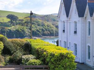 a white house with bushes next to a river at 4 The Elms in Salcombe