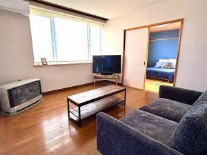 a living room with a couch and a tv at Olive retreat Sapporo 札幌市南区 一軒家の1フロア貸切 5名まで 2ベッドルーム 無料駐車場 登山 スキー場への好アクセス in Sapporo