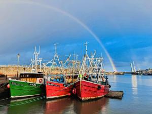 three boats are docked in the water with a rainbow at Ritson Wharf in Maryport +14 photos