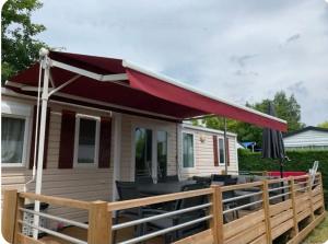 a tiny house with a red awning on a deck at Mobil home in Biscarrosse