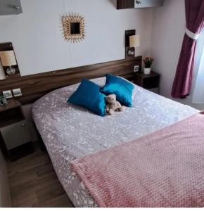 a teddy bear sitting on a bed with blue pillows at Mobil home in Biscarrosse