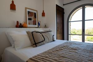 a bedroom with a bed with white sheets and a window at Villa CAMILLE in Ersa