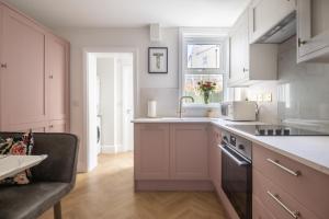 a kitchen with white cabinets and a sink at The Rosemont in Royal Tunbridge Wells +43 photos