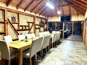 a dining room with a wooden table and white chairs at Casa Darius in Novaci-Străini