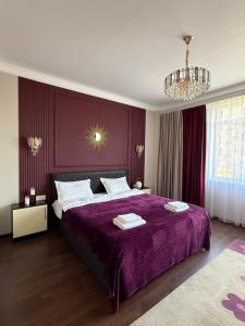 a bedroom with a purple bed and a chandelier at Ala-Too Central Square Residence in Bishkek