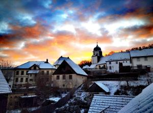 a snow covered village with a church and a sunset at Ferienhaus am Jakobsberg in Königsfeld
