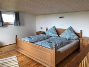 a bedroom with a large wooden bed with blue pillows at Ferienhaus am Jakobsberg in Königsfeld