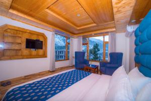 a bedroom with a bed and two blue chairs at Snow City's Montana Blues Resort Manali - Heated & Air-Cooled Stay in Manāli