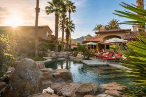 a backyard with a pool with rocks and a house at Villa Merion at PGA West | Grand Tuscan Estate in La Quinta