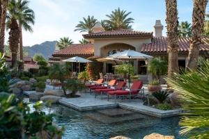 a resort with a pool with chairs and umbrellas at Villa Merion at PGA West | Grand Tuscan Estate in La Quinta