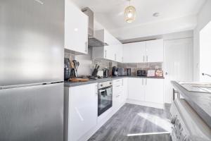 a kitchen with white cabinets and a stainless steel refrigerator at Colchester 4BR Home, Sleeps 8, Fast WiFi, Perfect for Contractors in Hythe