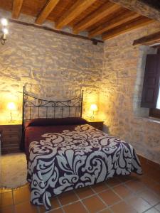 a bedroom with a black and white bed in a stone wall at Las Casas del Duraton in Urueñas