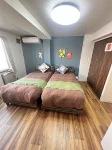 two beds in a room with wood floors at ヴィオラ菊水 in Sapporo