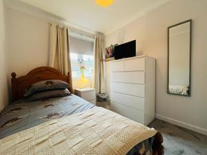 a bedroom with a bed with a dresser and a mirror at Inas Place in Caol