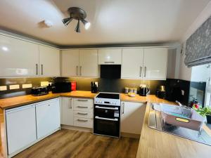 a kitchen with white cabinets and a black stove top oven at Inas Place in Caol