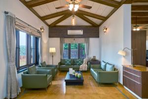 a living room with green couches and a ceiling at SaffronStays The Devrai by the Sea in Bhogwe
