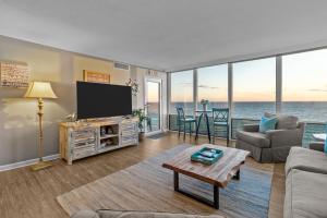 a living room with a tv and a couch and a table at Beachfront Condo/ Pool/ Surfing/ Fishing / EW 1202 in Virginia Beach
