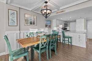 a kitchen and dining room with a wooden table and green chairs at Beachfront Condo/ Pool/ Surfing/ Fishing / EW 1202 in Virginia Beach