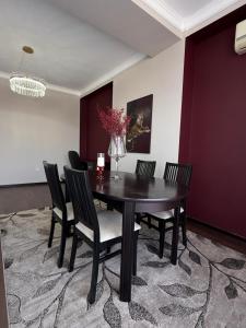 a dining room table with chairs and a vase of flowers at Ala-Too Central Square Residence in Bishkek