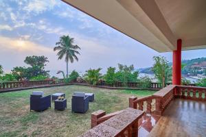 a patio with chairs and a view of the water at SaffronStays The Devrai by the Sea in Bhogwe
