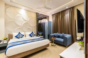 a bedroom with a large bed and a blue chair at Hotel Bella Express in New Delhi