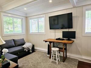 a living room with a couch and a tv on the wall at Captain Cottage in Bowen Island