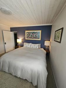 a bedroom with a white bed and two lamps at Captain Cottage in Bowen Island
