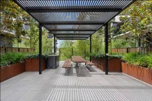 a picnic table and benches under a pergola at Balcony Apt with 1 Bedroom in Belconnen