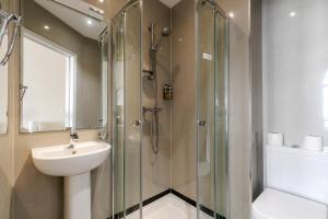 a bathroom with a glass shower and a sink at Mina Hotel by PLI in London