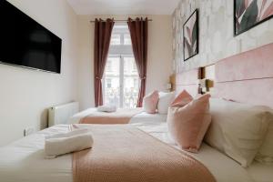 a bedroom with two beds and a tv on the wall at Mina Hotel by PLI in London +9 photos