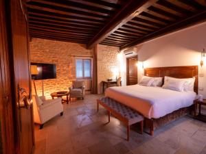 a bedroom with a bed and a couch and a tv at Les Remparts Hôtels et Demeures Historiques in Beaune