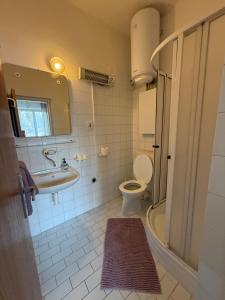 a bathroom with a sink and a toilet and a mirror at Penzion Vis a Vis in Třebíč