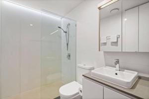 a white bathroom with a sink and a toilet at Modern 1BR Views in Belconnen in Belconnen