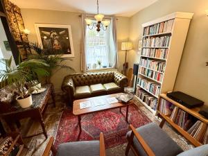 a living room with a leather couch and a book shelf at The Old Bakehouse in Colyton