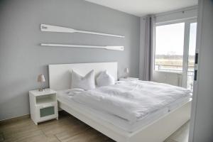 a white bedroom with a white bed and a window at Lagunenstadt am Haff - Fewo 093 Ree! in Ueckermünde