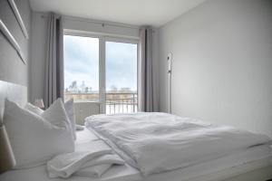 a white bedroom with a bed and a window at Lagunenstadt am Haff - Fewo 093 Ree! in Ueckermünde