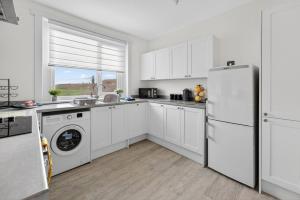 a kitchen with white cabinets and a refrigerator at Troon Golf by the Sea in Troon