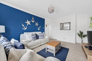 a living room with a couch and a blue wall at Troon Golf by the Sea in Troon