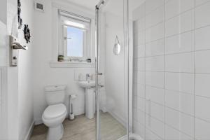 a white bathroom with a toilet and a sink at Troon Golf by the Sea in Troon