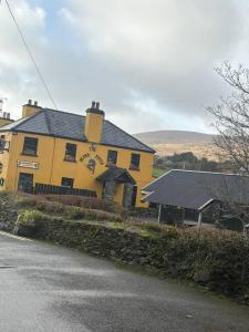 a yellow building with a black roof on a street at Stylish Holiday Home - Caherdaniel in Caherdaniel