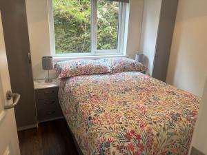 a bedroom with a bed with a flowered bedspread and a window at Stylish Holiday Home - Caherdaniel in Caherdaniel