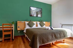 a bedroom with a bed with a green wall at Casa Os Manos - Hikers Lodge in Santana