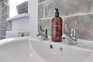 a bottle of alcohol sitting on a bathroom sink at Colchester 4BR Home, Sleeps 8, Fast WiFi, Perfect for Contractors in Hythe +26 photos